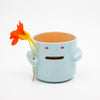 Ceramic mug with face holding a flower on a white background
