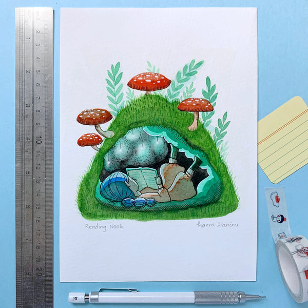 Illustration of a person reading in a cave with mushrooms, placed on a blue background with stationery items.