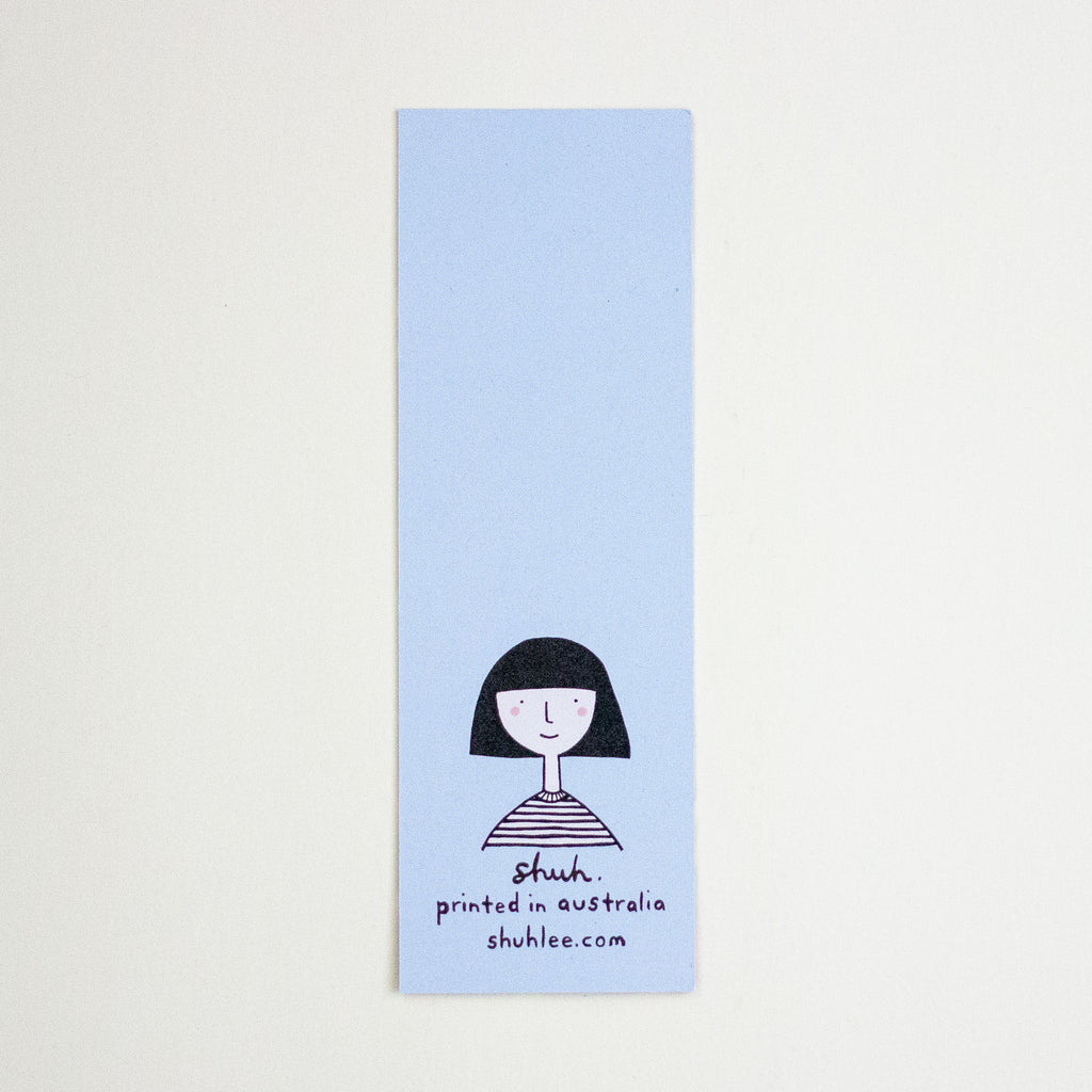 A tall, narrow light blue bookmark with a simple black line drawing of a person with a bob haircut and the text 'shuh. printed in australia shuhlee.com'