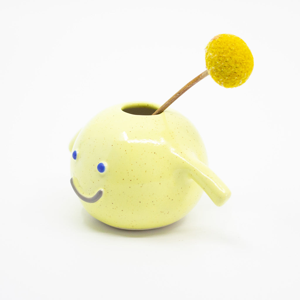 A Side view of the sasha vase holding a flower, yellow