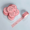 Pink washi tape with decorative designs on a light blue background