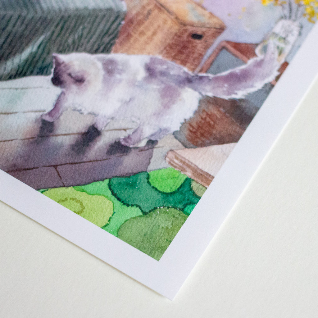 Corner of a watercolour painting of a cosy bedroom scene with a white cat walking across the floor.