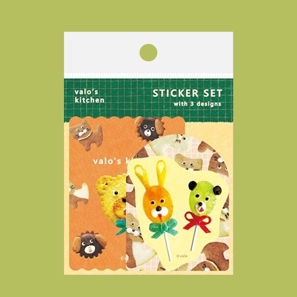 A cute sticker set from 'valo's kitchen' featuring three designs: a yellow bear lollipop, a green bear lollipop, and a sheet of cat-shaped stickers, displayed on a olive green background.