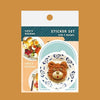 A sticker set from Valo's Kitchen featuring three breakfast-themed sticker designs: a dog toast, a bear-shaped dish, and a strawberry dessert, displayed on a brown background with the packaging card behind them.