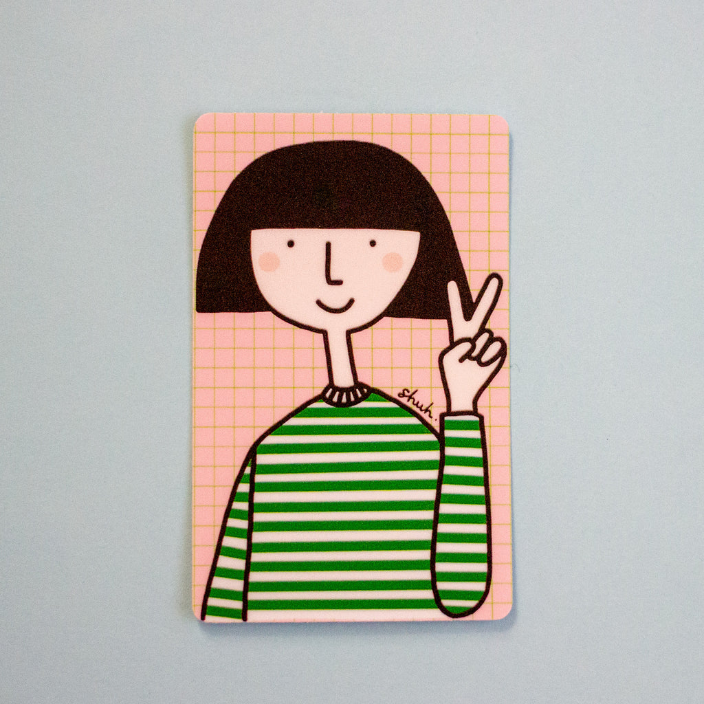 A rectangular art print or card featuring a minimalist cartoon illustration of a person with a black bob haircut, pink grid background, and green-and-white striped shirt, shown against a light blue background.