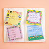 An open notebook or card set on a peach background, showing four colourful handwritten note cards with positive messages: 'Be kind to yourself!', 'You mean the world to me!', 'Resilient Kindness Courage Hope!', and 'What's the next right thing to do!'.