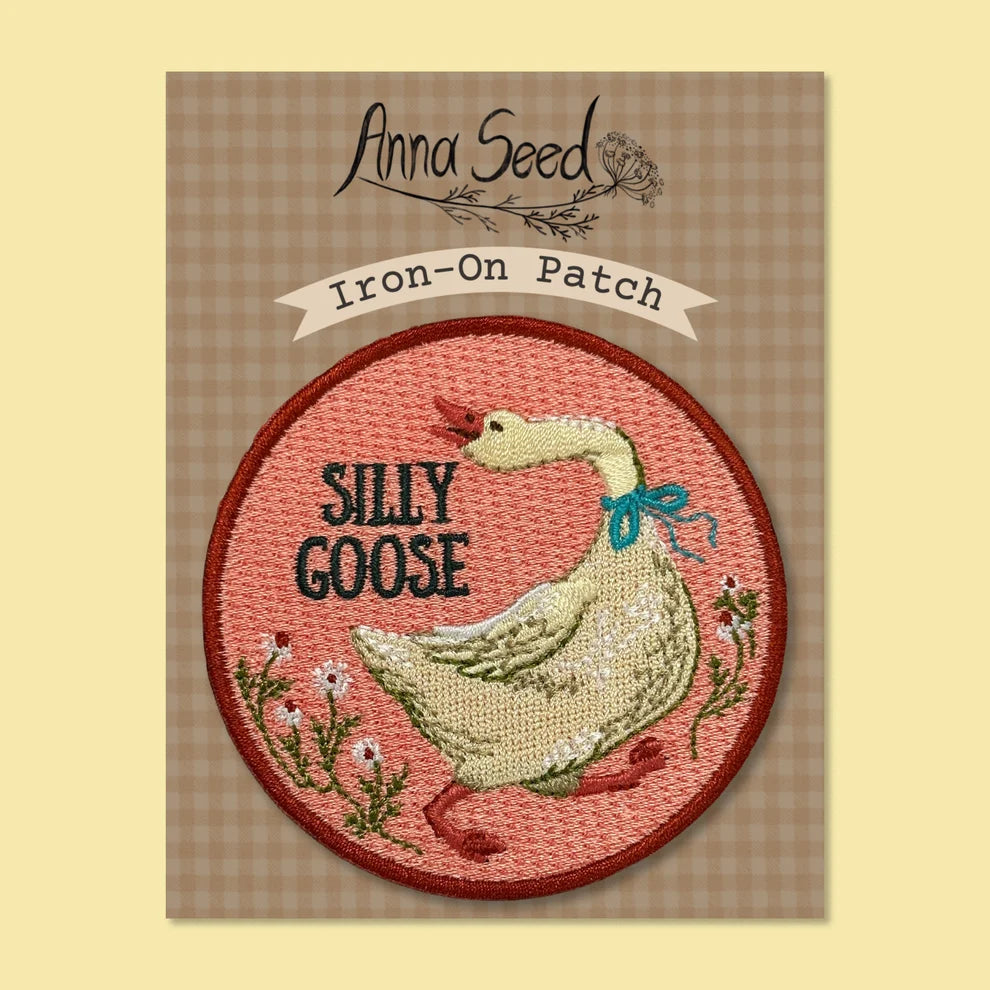 Iron-on patch with a goose design on a checkered backing card. 