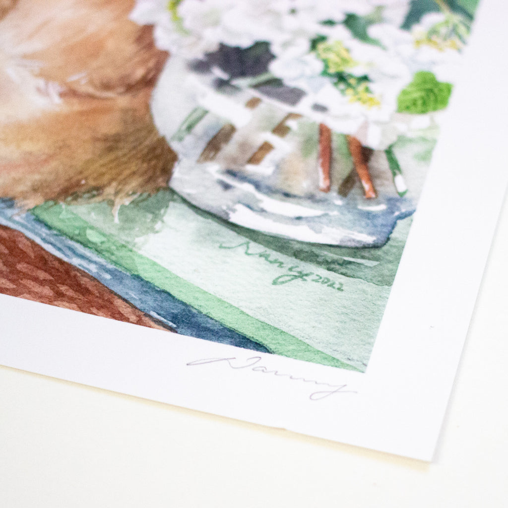 A close-up of a watercolour art print featuring a fluffy brown animal, white flowers in a vase, and green painted surfaces, with a white border and a faint artist signature near the bottom.