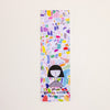 A tall, narrow printed  bookmark with a colourful abstract pattern and a simple black-haired girl illustration near the bottom. The text 'shuh. and 'printed in australia' with 'shuhlee.com'.