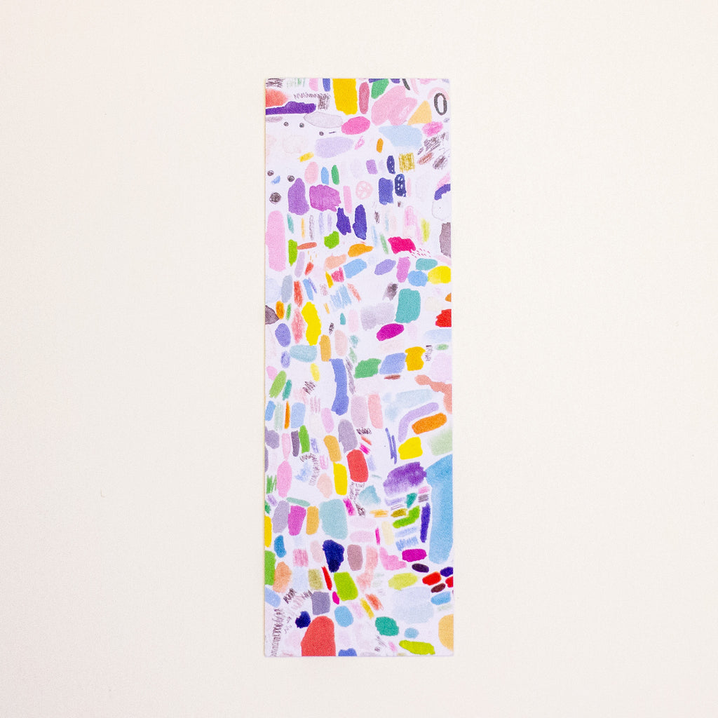 A tall, narrow bookmark featuring a colourful abstract watercolour splatter pattern on a white background, displayed vertically against a light beige backdrop.