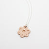 Necklace with a pink flower-shaped pendant on a light gray background