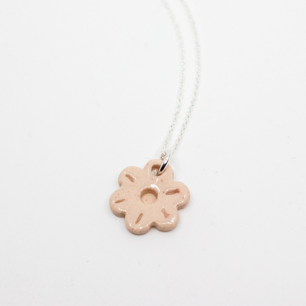 Necklace with a pink flower-shaped pendant on a light gray background