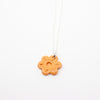 Orange flower-shaped pendant on a white background