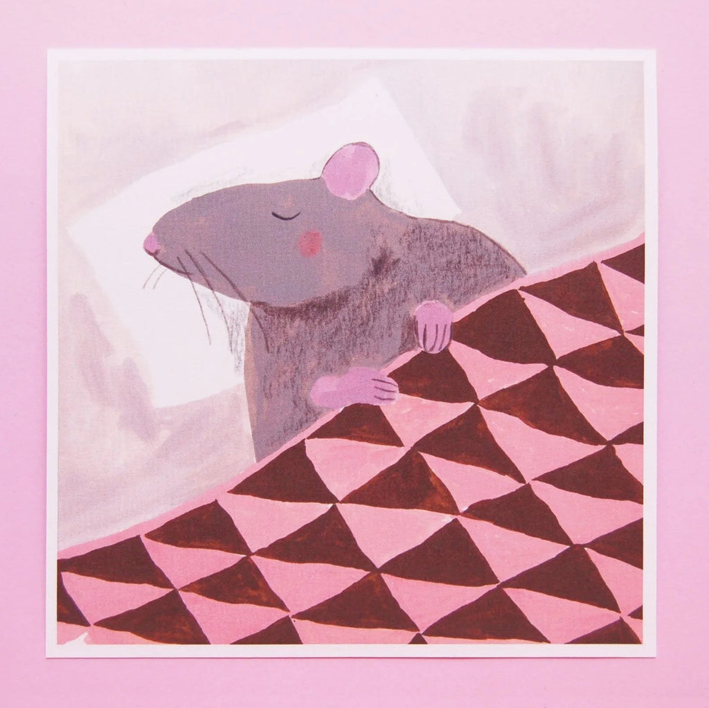 An illustrated square print of a rat sleeping on a pillow and tucked in under a blanket with white border photographed against a pink backdrop. 