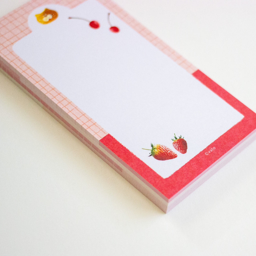 A stack of cute notepad sheets with a pink and red grid border, decorated with cherry and strawberry illustrations on a clean white background.