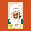 A small notepad with a cute cartoon food and animal illustration on the cover. 
