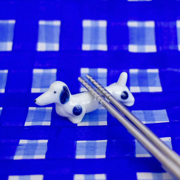 Dog-shaped ceramic chopstick rest on a blue checkered background