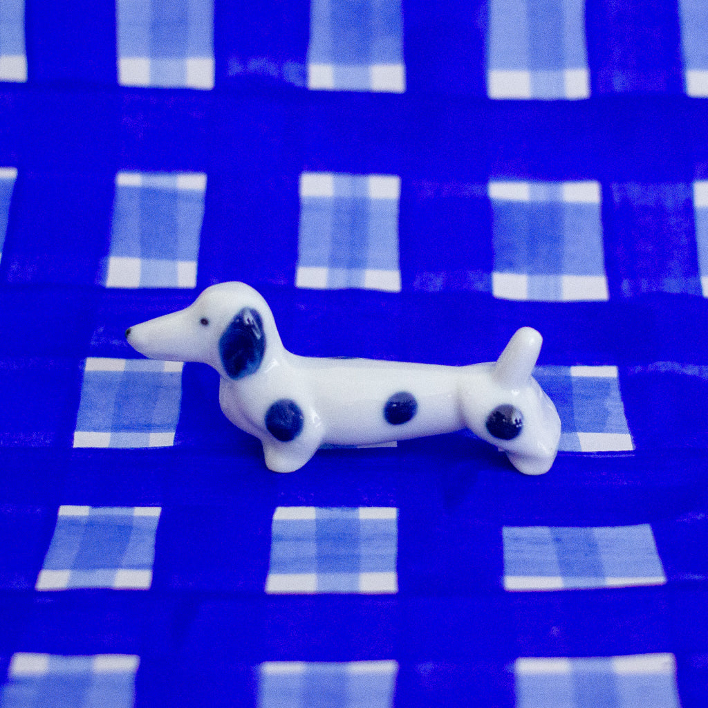 White dog figurine with blue spots on a blue checkered background