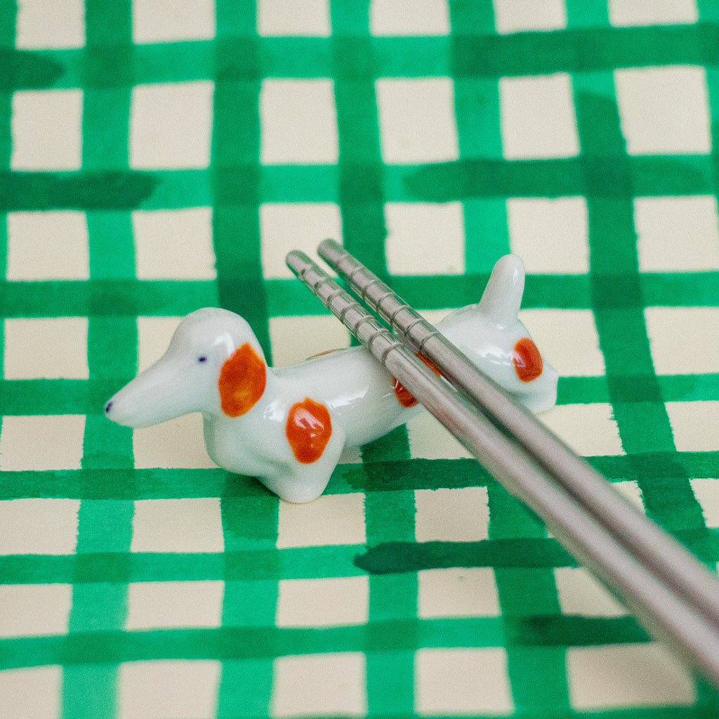 Dog-shaped ceramic chopstick rest on a green and beige checkered background