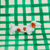 Small ceramic dog figurine with brown spots on a green and white checkered background