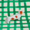 Small ceramic dog figurine with brown spots on a green and white checkered background