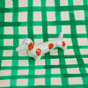Small ceramic dog figurine with brown spots on a green and white checkered background