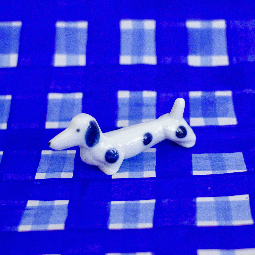 White ceramic dog figurine with blue spots on a blue checkered background