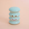 Small ceramic figurine with a smiley face on a peach background