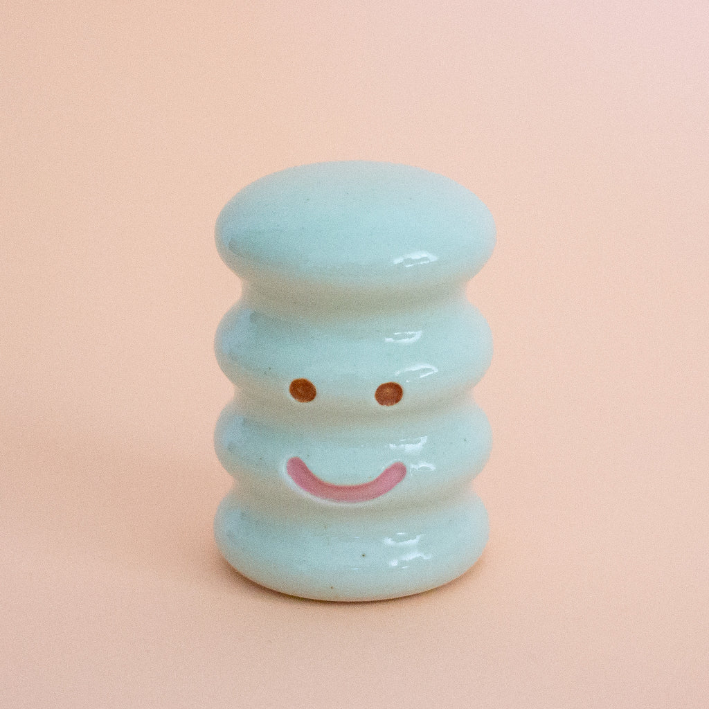 Small ceramic figurine with a smiley face on a peach background