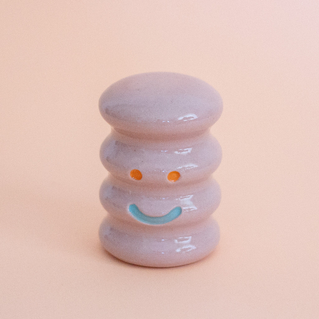 Small ceramic figurine with a smiley face on a peach background