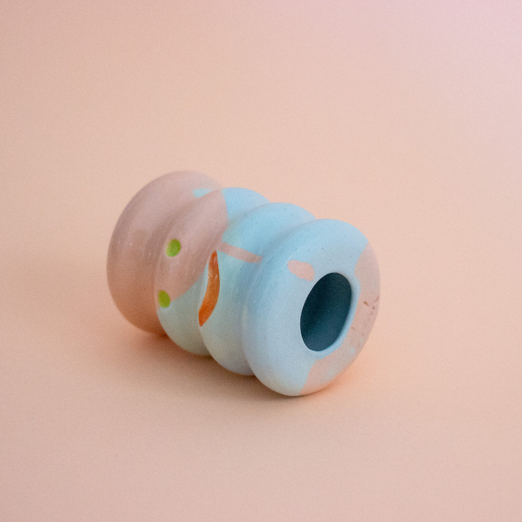 Small ceramic figurine with a smiley face on a peach background