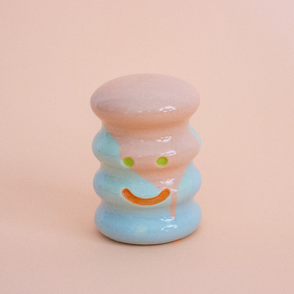 Small ceramic figurine with a smiley face on a peach background