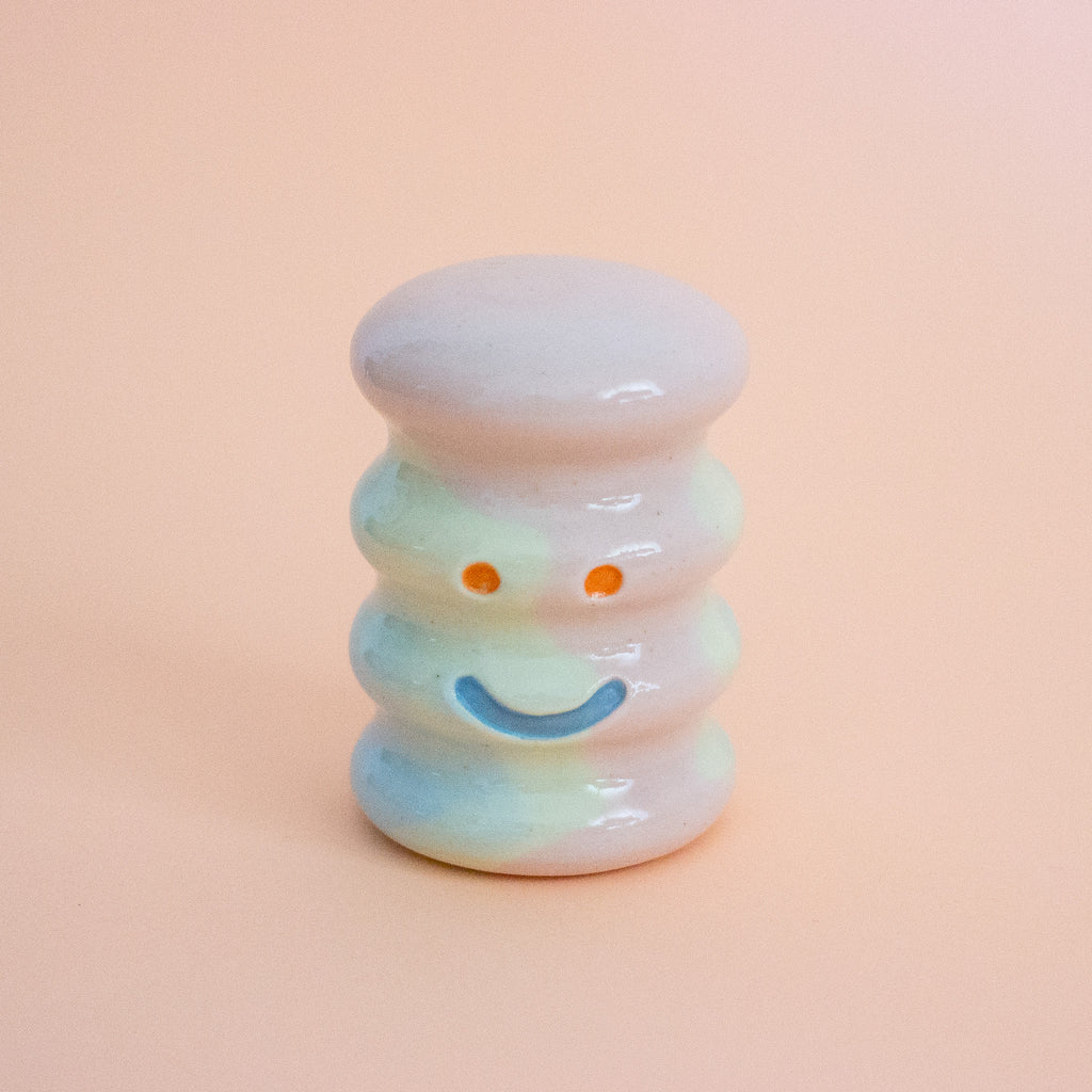 Small ceramic figurine with a smiley face on a peach background