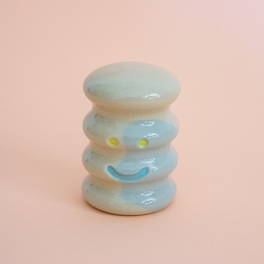 Small ceramic figurine with a smiley face on a peach background