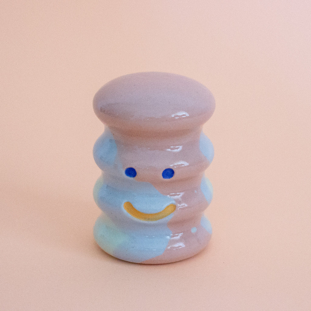 Small ceramic figurine with a smiley face on a peach background