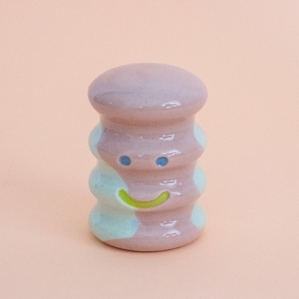 Small ceramic figurine with a smiley face on a peach background