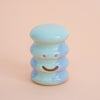 Small ceramic figurine with a smiley face on a peach background