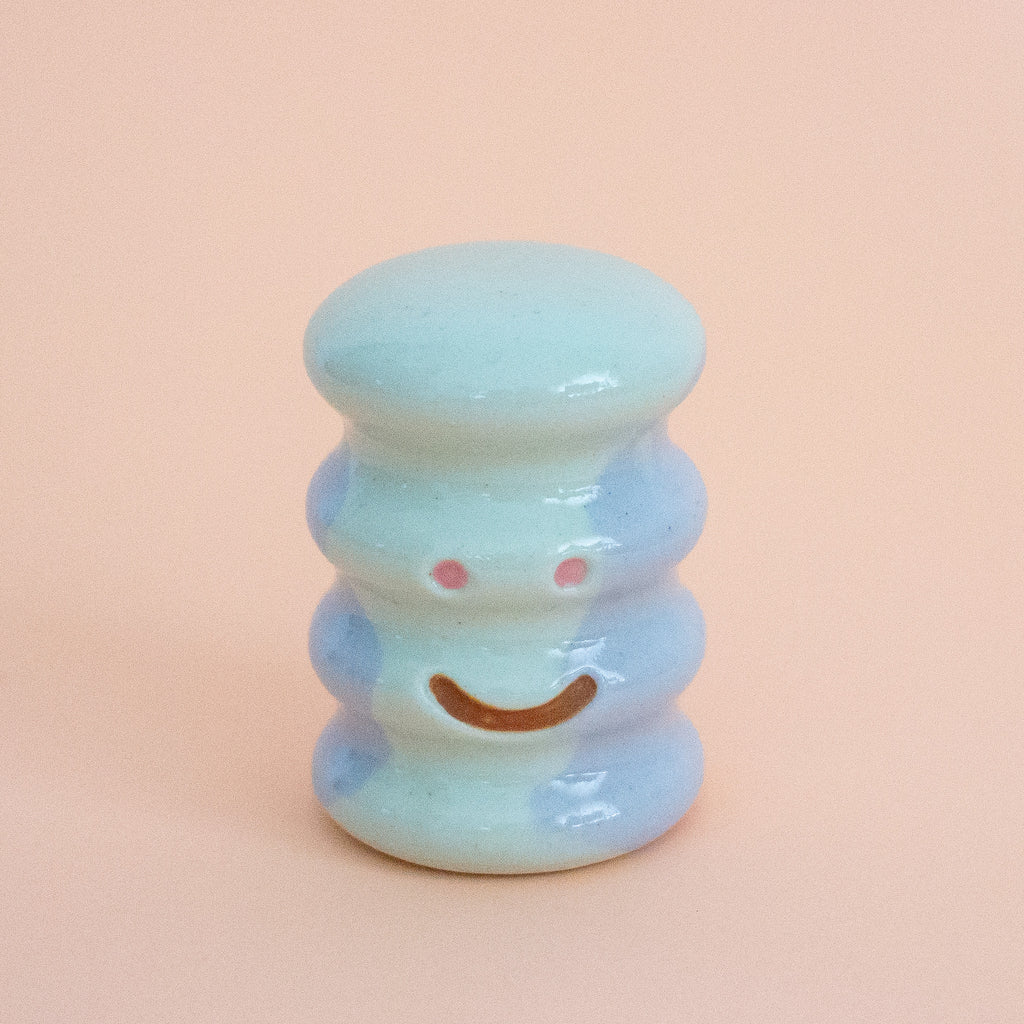 Small ceramic figurine with a smiley face on a peach background