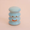 Small ceramic figurine with a smiley face on a peach background