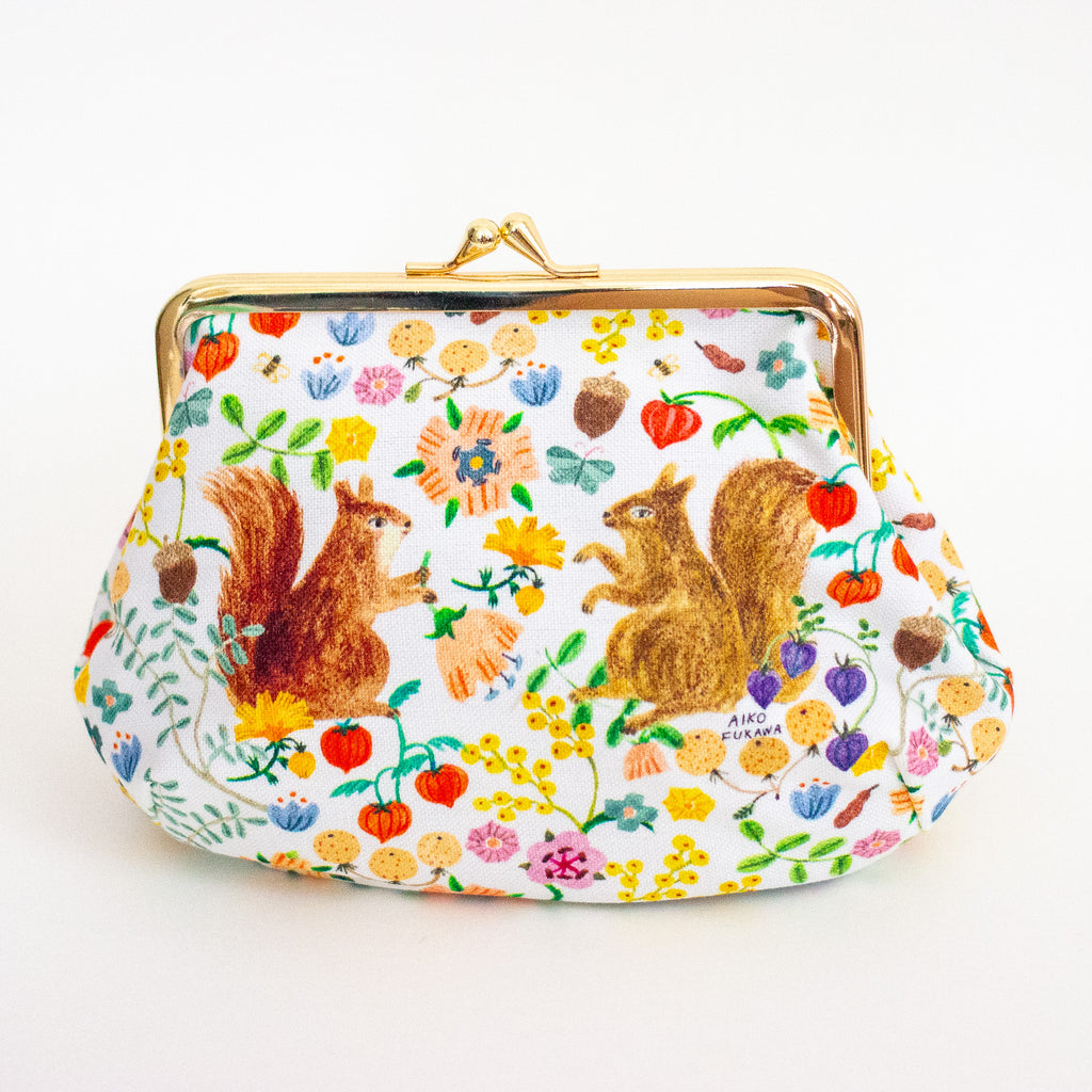 A white kiss-lock clutch purse featuring a colourful pattern of squirrels, flowers, and acorns, framed with a gold-tone metal clasp.