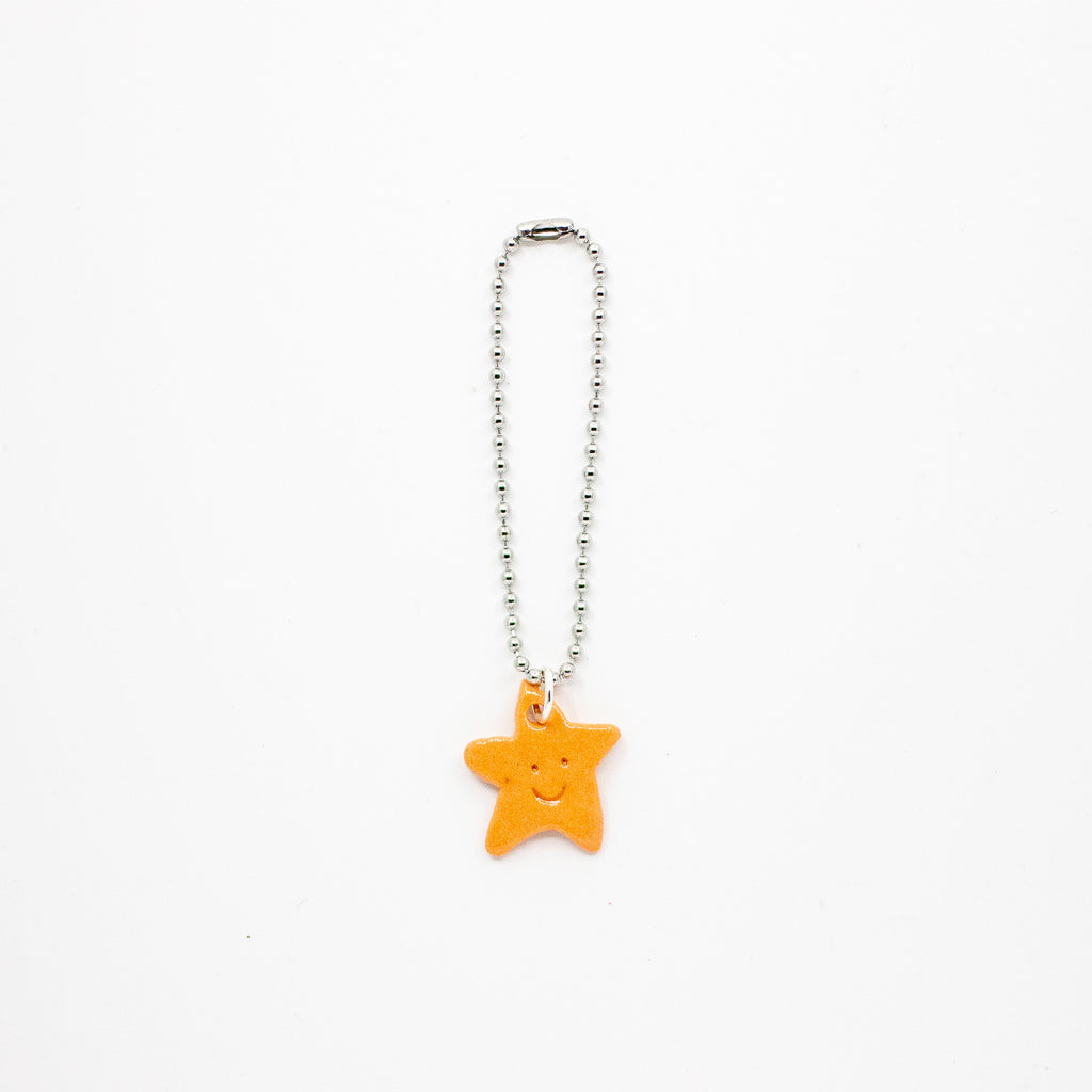Orange star-shaped keychain on a silver chain against a white background