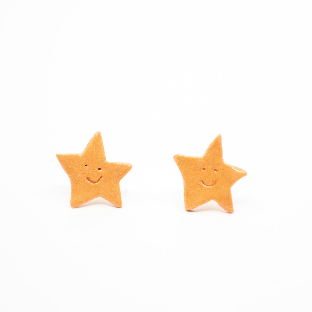 Two orange star-shaped earrings on a white background