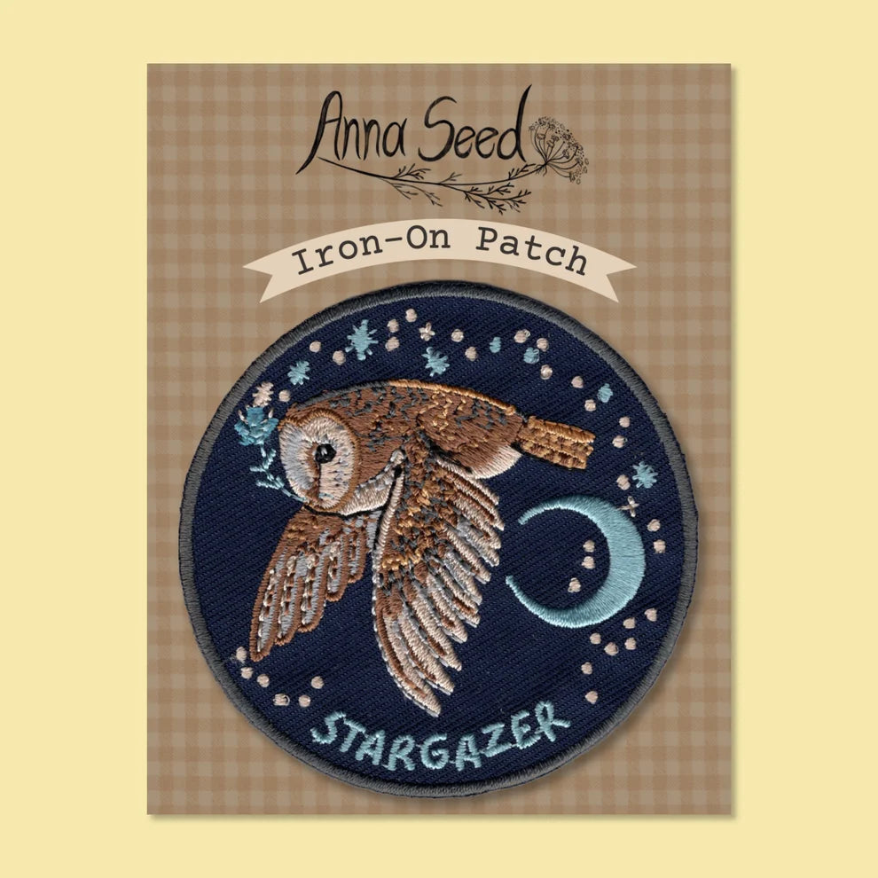 Iron-on patch with an owl design and 'Stargazer' text, branded 'Anna Seed', on a checkered background.