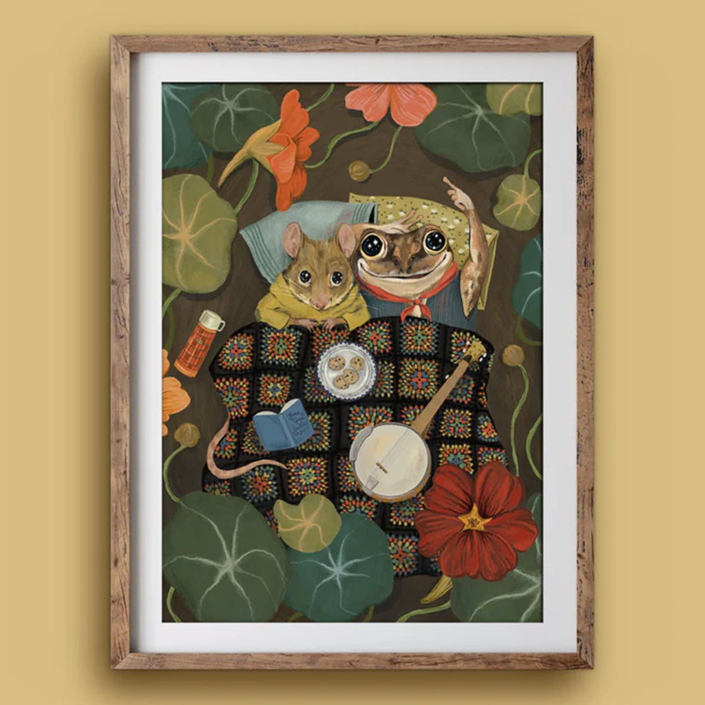 Framed artwork of two animals in a decorative setting with flowers and a banjo.