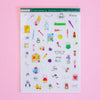 A sheet of colourful stationery stickers displayed on a solid pink background. The sticker sheet contains various cute illustrations of pens, notebooks, flowers, and office items.