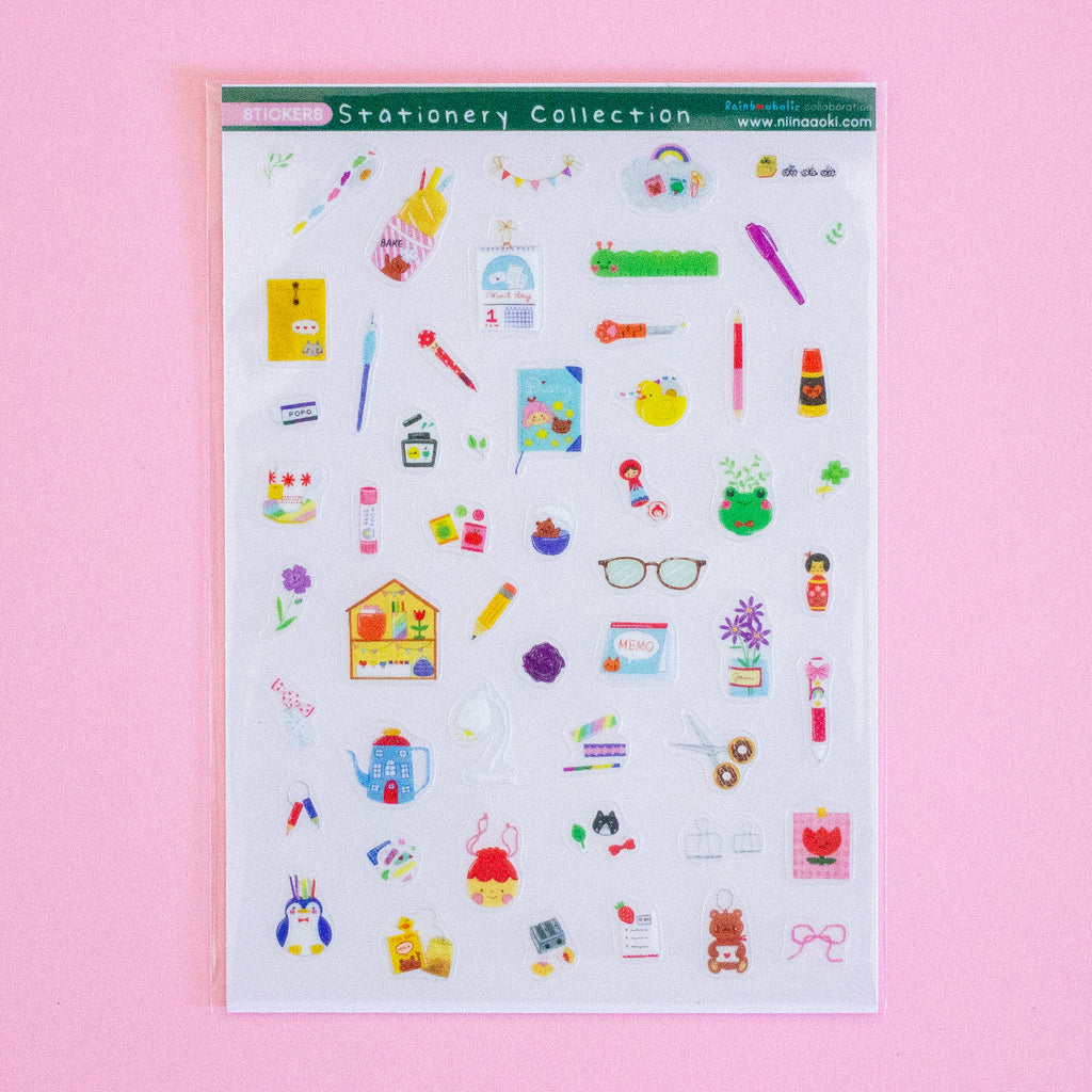 A sheet of colourful stationery stickers displayed on a solid pink background. The sticker sheet contains various cute illustrations of pens, notebooks, flowers, and office items.