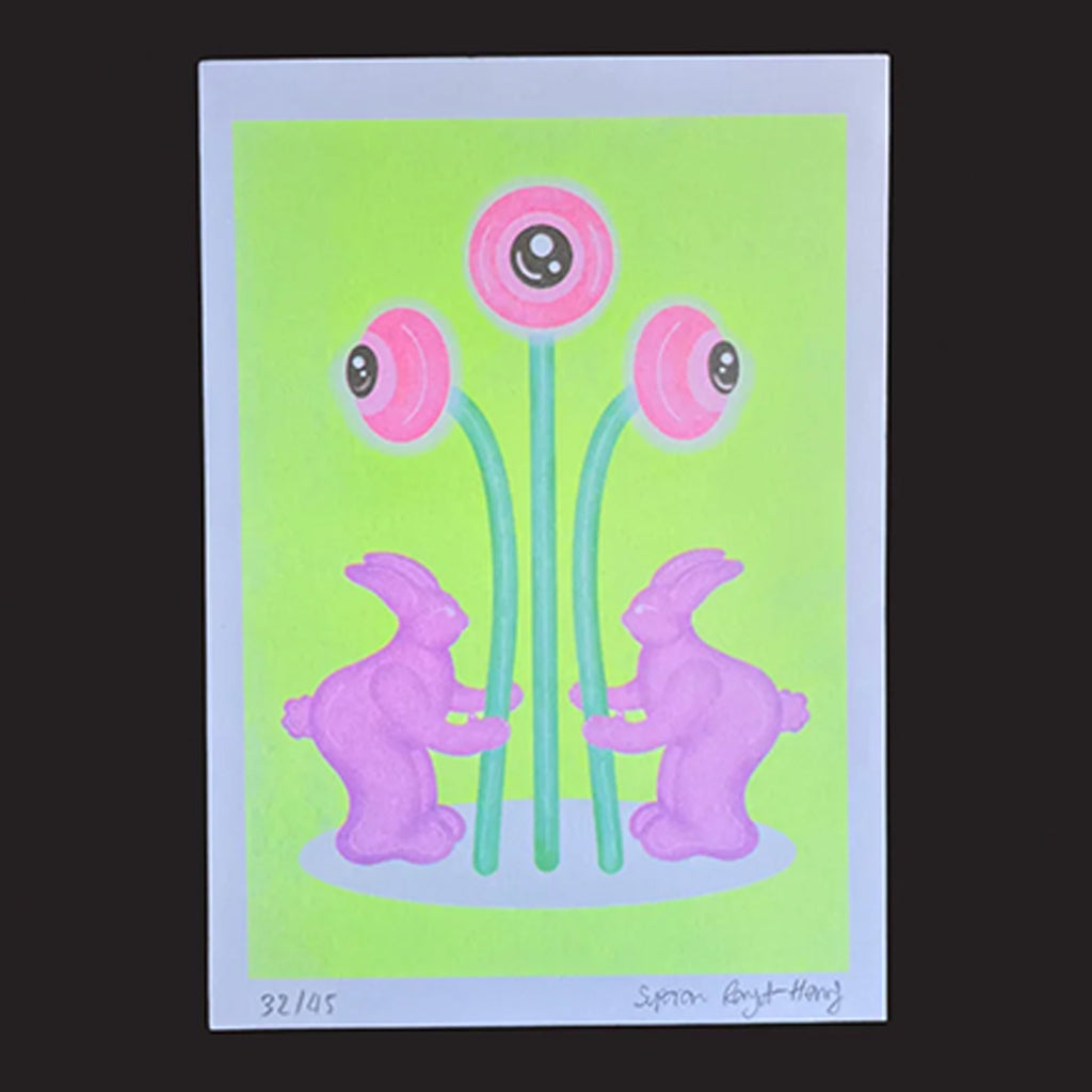 A rectangular art print featuring two pink rabbits facing each other in front of three pink flowers with large black-and-white eyes on a bright lime green background, photographed against a dark charcoal backdrop.