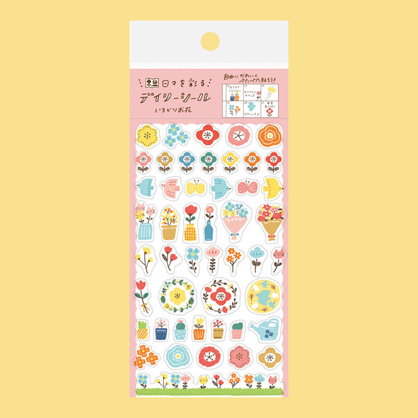 A sheet of decorative stickers with colourful floral and nature-themed designs, including flowers, butterflies, birds, leaves, and small illustrations, shown on a pink backing card against a pale yellow background.