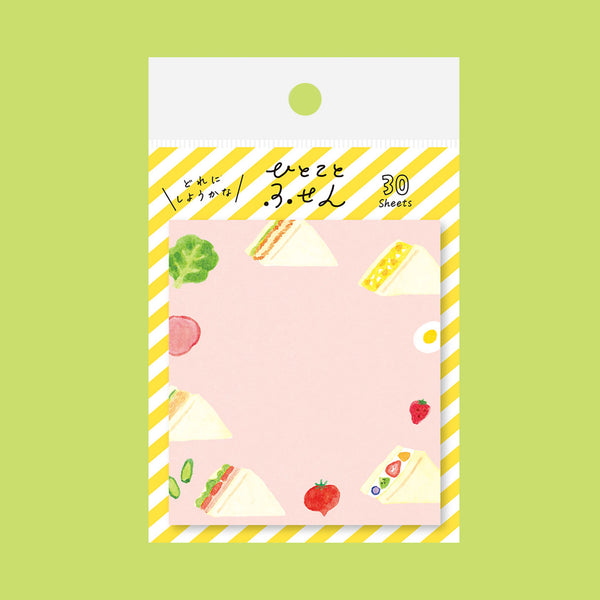 A pastel pink notepad with cute watercolor illustrations of food items like sandwiches, strawberries, and tomatoes, packaged in a white card with yellow diagonal stripes and Japanese text.