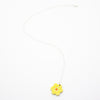 Yellow flower-shaped pendant on a white chain against a white background